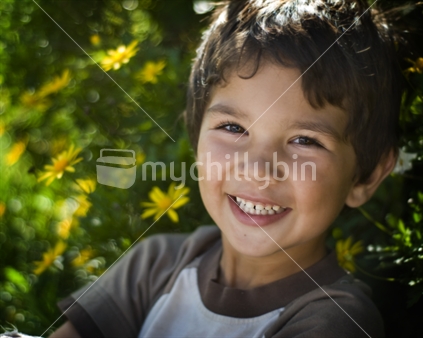 A happy young boy giggles amongst yellow flowers (soft focus)