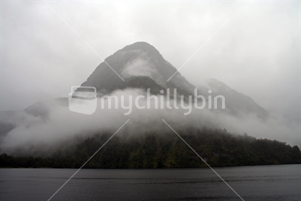 Mist shrouds a mountain in Doubtful Sound, South Island, New Zealand