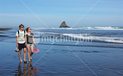 A young man and a young woman walking at the beach, Karekare, West coast, Auckland
