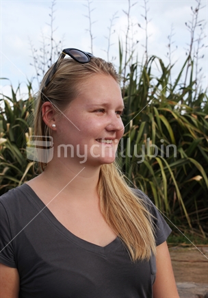 Beautiful young woman, with NZ flax beyond