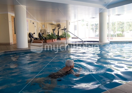 An apartment exercise area (focus bikes)with elderly woman in pool.