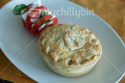 An iconic Kiwi meat pie served with a tomato , feta and basil salad (raised ISO)