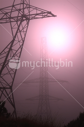 Light shining through mist around power pylons.