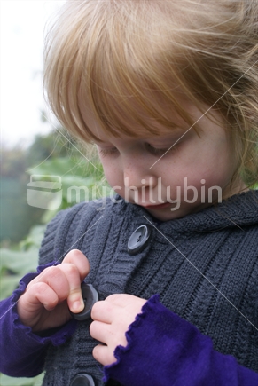 Close up of a young girl buttoning up her own jersey