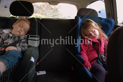 Two preschoolers asleep in the back seat of a car
