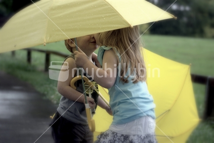 children sharing a kiss in the rain, 