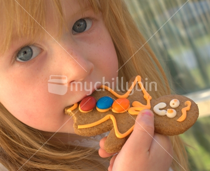 Young girl eating a gingerbread man cookie