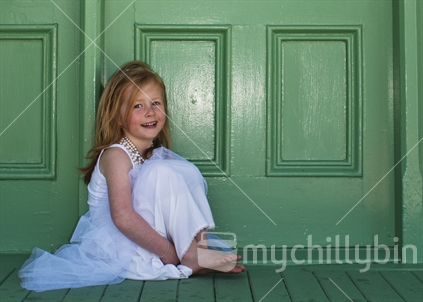 Young girl in white, on a green doorstep