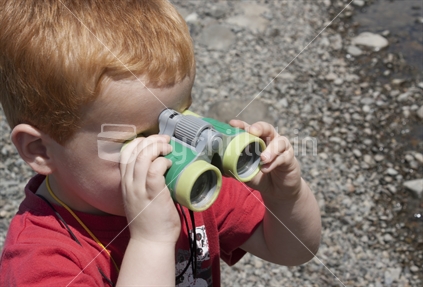 A little boy looks through his binoculars
