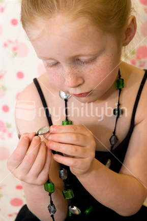 A young New Zealander girl inspects her necklace of beads