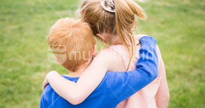 A young boy and girl with arms around each-other
