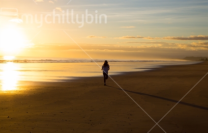A lone runner on Ohope Beach in the sunrise