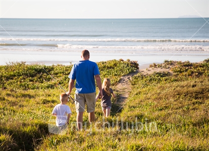 A father walks his two children to the beach