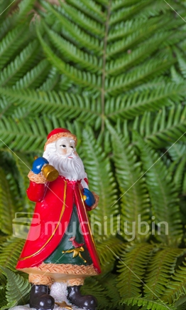 Santa Claus figurine on a fern background.