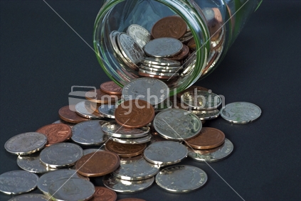 New Zealand coins in a savings jar on a black background.