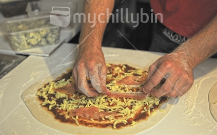 Chefs hands making pizza topping 