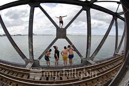 Maori people jumping into Tauranga Harbour, from the railway bridge
