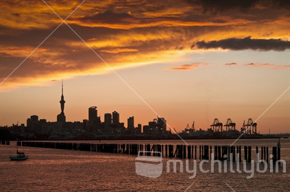 Auckland downtown sihouetted at sunset, Orakei breakwater in foreground.