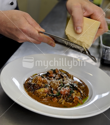 Parmigiana being grated onto a meal