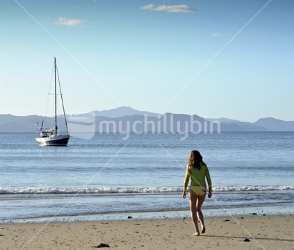 Girl on beach and moored yacht.