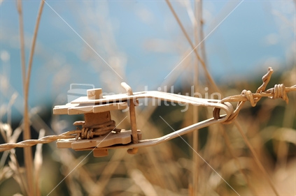 Ratchet on wire fence in front of wild grasses