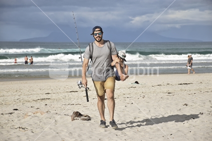 Father carrying son on Beach