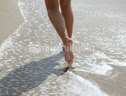 Bare legs and feet walking through water at beach, Coromandel, New Zealand