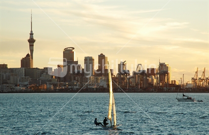 Yacht in Waitemata harbour in front of Auckland Skyline at sunset, New Zealand