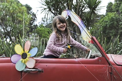 Smiling child in old open top car, New Zealand