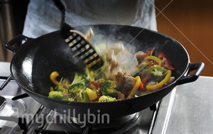 Fresh chicken and vegetables being stir fried in a wok
