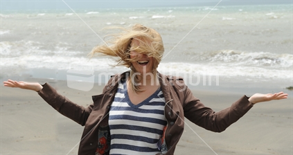 Girl on windy Kohimarama beach in Auckland, enjoying hair blowing wild.