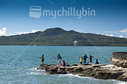 Families fishing off rocks in Auckland Harbour