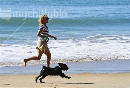 Woman running with dog on beach.