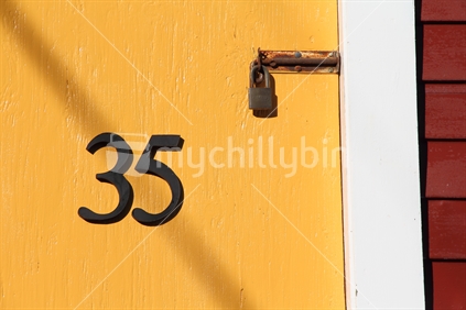 Number 35 on yellow door, with rusty padlock