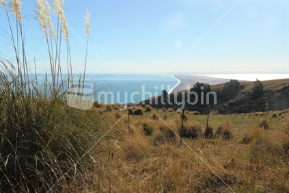 View along Kaitorete Spit, Christchurch, from upland Banks Peninsula. Sunlight reflects off Lake Ellesmere to the right 