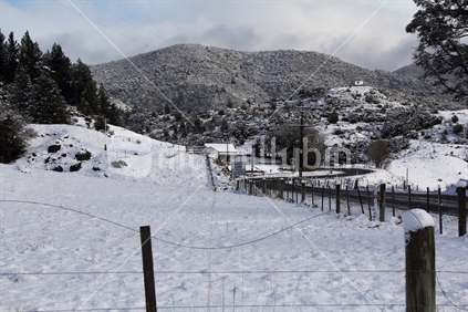 Early snowfall on the Takaka Hill road covers the hillsides and houses