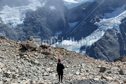 Woman walks across Mueller ridge, with hanging glaciers of Mt Sefton in the background
