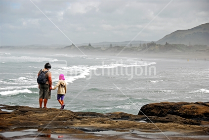Grandmother and her granddaughter looking at Muriwai Beach, New Zealand