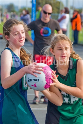 Two netball players wrestle for the ball