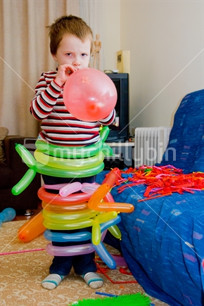 Boy wrapped in balloons blows one up at a birthday party in New Zealand.