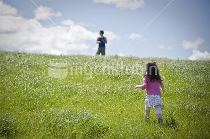 Little girl running up paddock to daddy