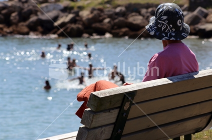 Older lady watching children playing in the water.