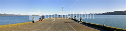 A panorama of Petone Wharf, on a calm Wellington day with people walking and fishing.