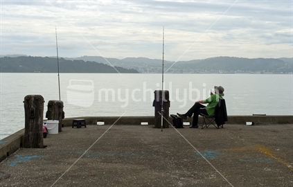 A man with two rods waits for a bite at Days Bay in Wellington.