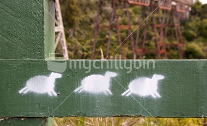 Painted sheep on a barrier fence, beside a railway viaduct

