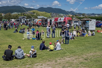Kapiti Coast food fair at Paraparaumu Mazengard Reserve 2016. Shows some of the crowd enjoying the atmosphere with a row of food trucks lining up