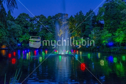 The annual festival of lights at Pukekura Park in New Plymouth. The coloured lights float in one of the ponds and a fountain plays. The trees are illuminated by lights as well