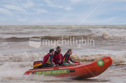 A team of lifeguards practicing with their inflatable rescue boat in a dirty lupmy sea
