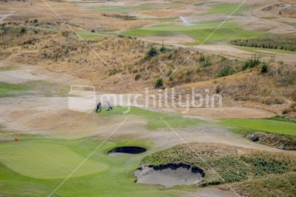 Paraparaumu golf course from an elevated position. Two golfers walking on the course.