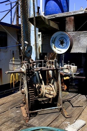 Old gantry winch on a wharf next to fishing boats in New Zealand.